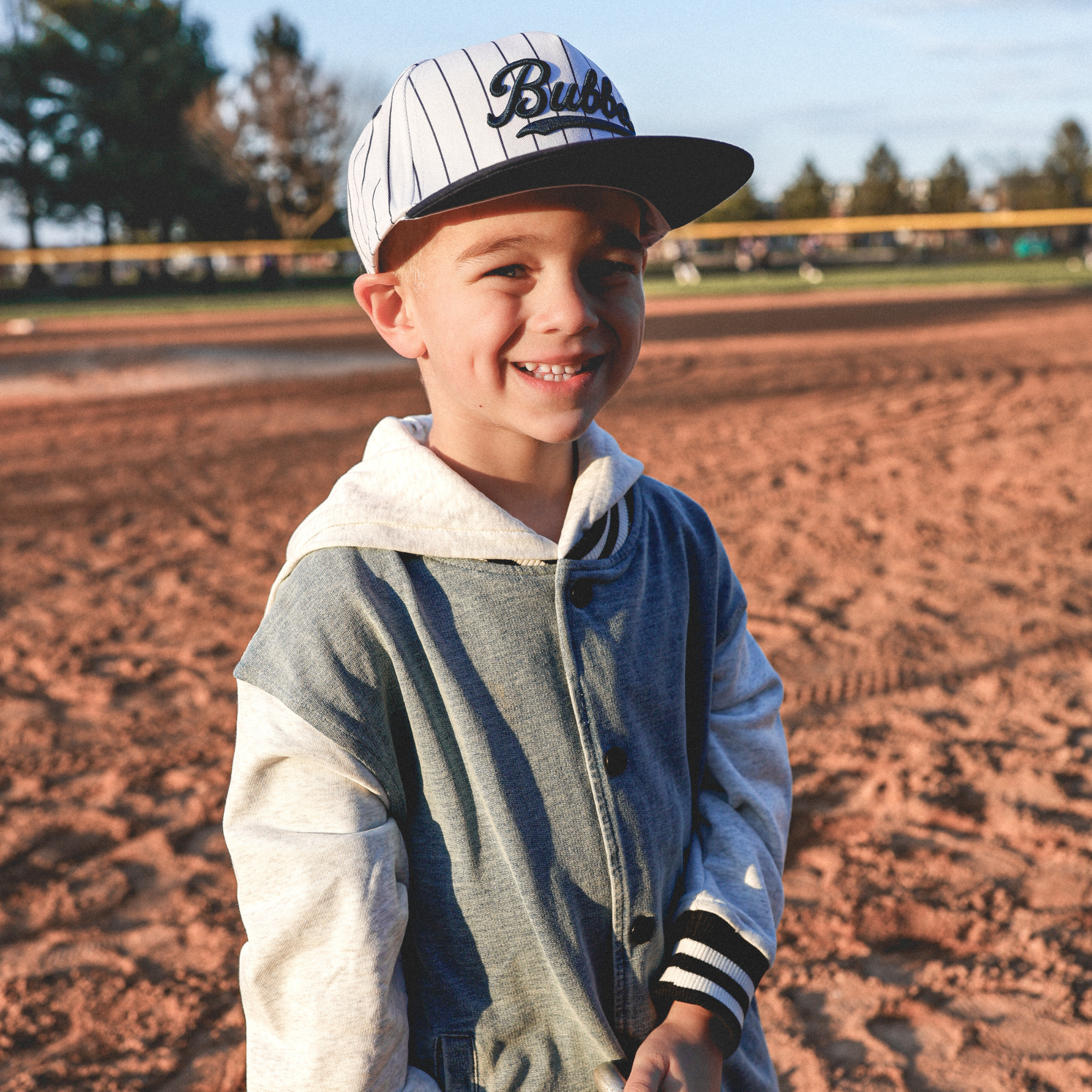 Lifestyle photo of toddler wearing Bubba embroidered snapback hat with navy pinstripes outdoors