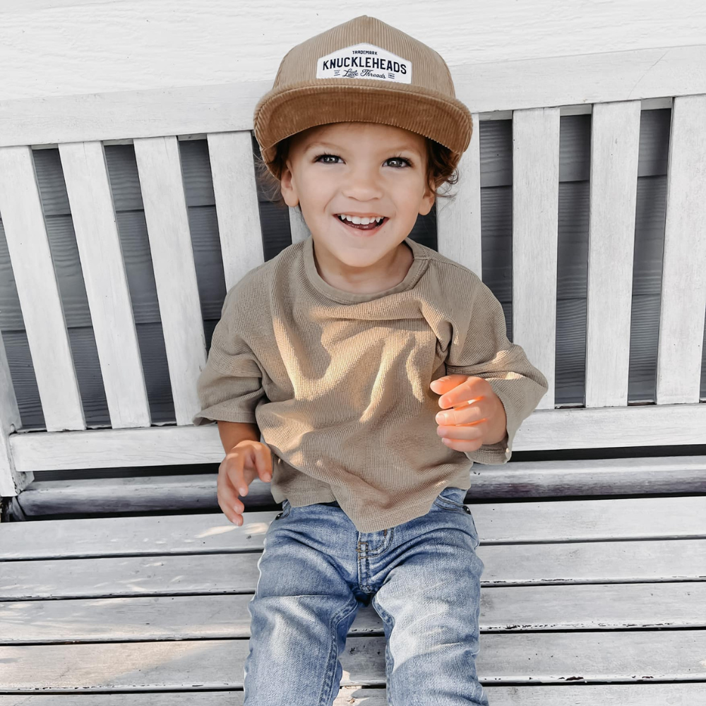 Image of Tan Corduroy Kids Trucker Hat with Knuckleheads Patch: A vintage-inspired and stylish accessory designed for kids. In a warm tan corduroy fabric, it showcases a striking Knuckleheads patch on the front. Elevate your child's style with this fashionable hat, perfect for adding a touch of texture to their outfits.