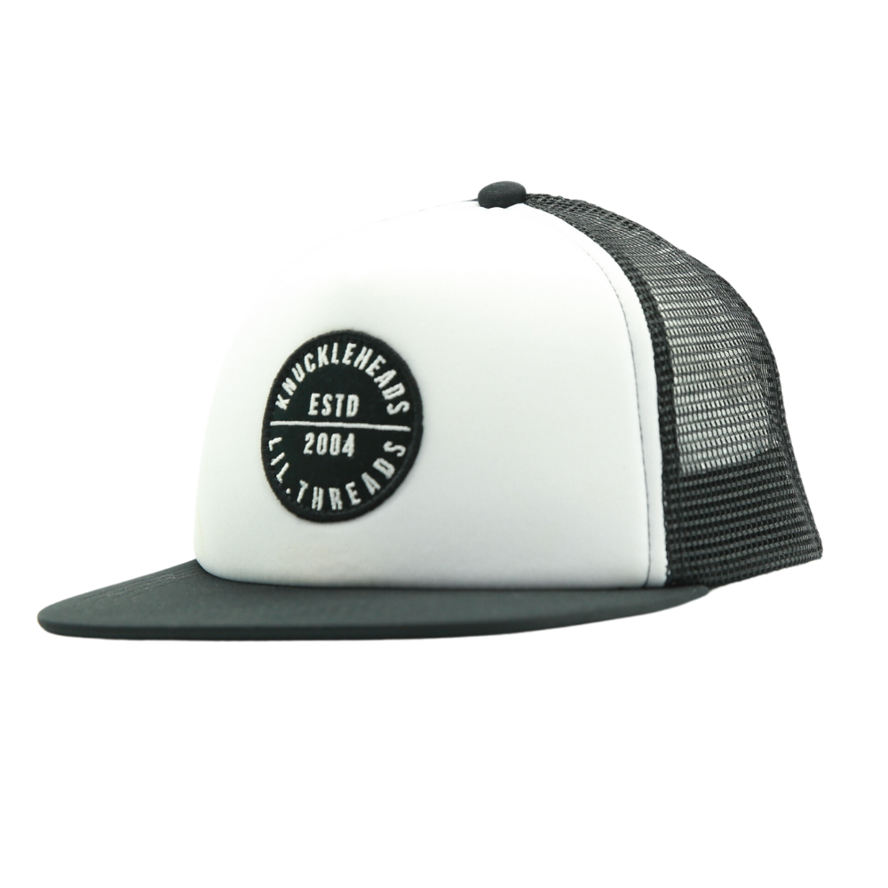 Presenting a Black and White Kids Trucker Hat featuring a classic Knuckleheads patch and practical sun mesh. This hat is designed for children, combining the timeless appeal of black and white with the iconic Knuckleheads patch. The addition of sun mesh provides both style and sun protection. A standout accessory in our collection, it adds flair and practicality to your little one's look.
