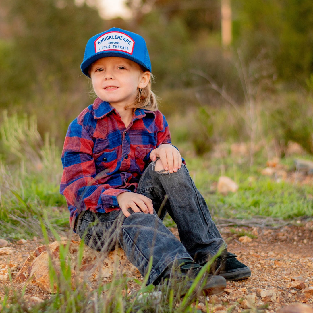 Meet the 'Blaine' Blue Kids Trucker Hat with Knuckleheads Patch: A trendy and stylish accessory designed for kids. The hat features a captivating blue hue and showcases a cool Knuckleheads patch on the front. Elevate your child's style with this fashionable hat, perfect for adding a pop of color to any outfit. Whether for adventures or everyday wear, the 'Blaine' blue trucker hat with Knuckleheads patch is a must-have addition to their wardrobe.