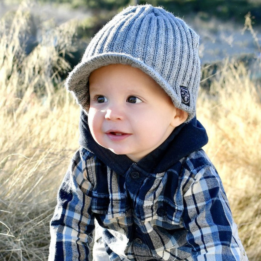 Image showcasing a grey beanie with a visor and Knuckleheads patch, designed for children. This versatile beanie combines style and functionality with its added visor and iconic Knuckleheads patch, making it an ideal choice for infants and toddlers. A standout piece in the collection of Infant hats, offering a perfect blend of practicality and charm.