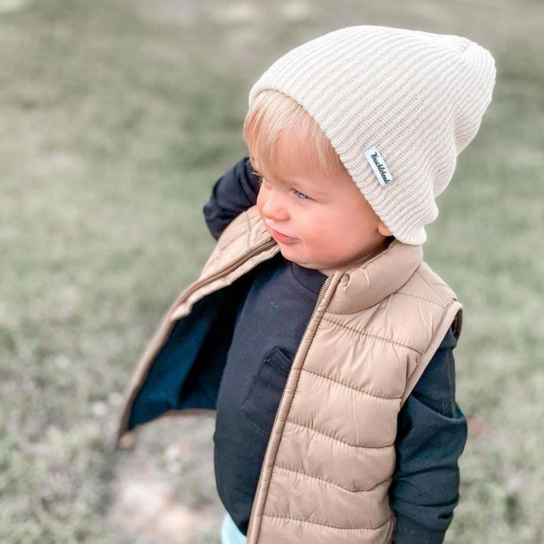 Image of a slouchy ivory beanie from Knuckleheads, designed for children. This versatile beanie offers a relaxed style with the Knuckleheads brand tag, suitable for infants and toddlers. A part of the charming collection of Infant hats for added appeal.