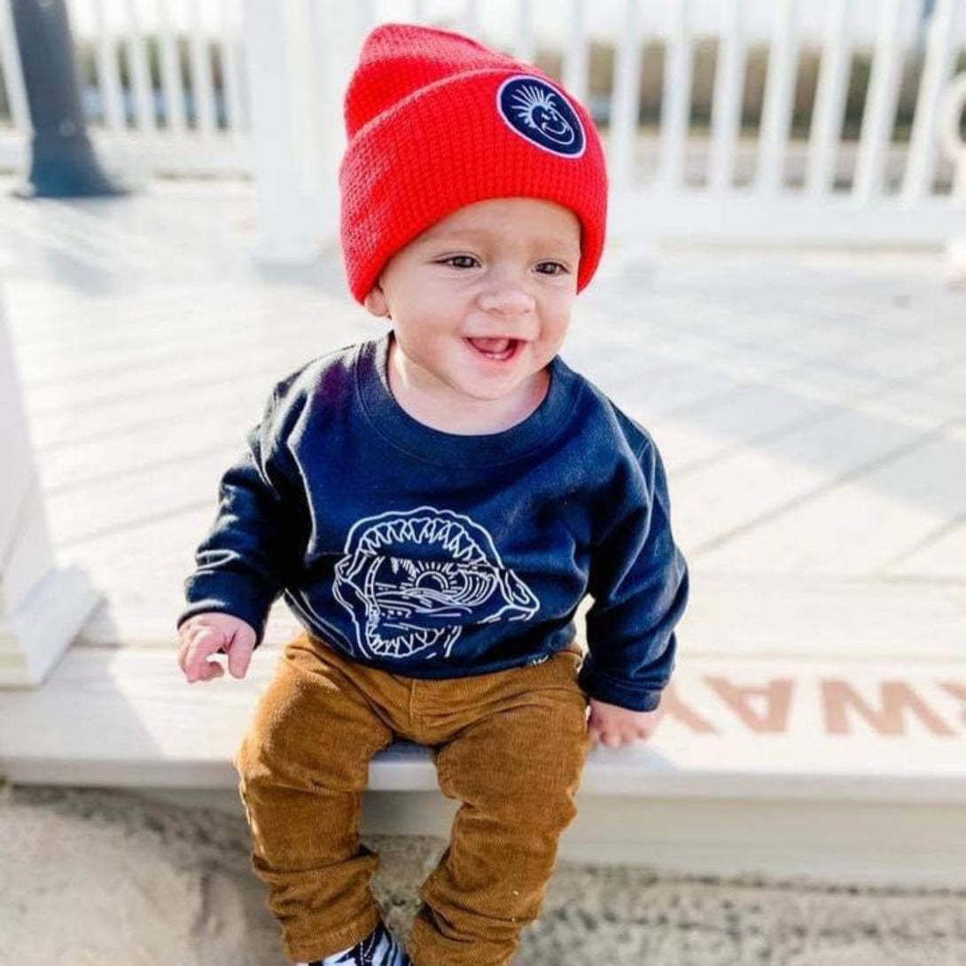 Image showcasing a fold-up red beanie from Knuckleheads, thoughtfully designed for children. This versatile beanie offers a classic style, complete with the Knuckleheads brand tag, ideal for infants and toddlers. A charming addition to the collection of Infant hats, elevating its appeal.