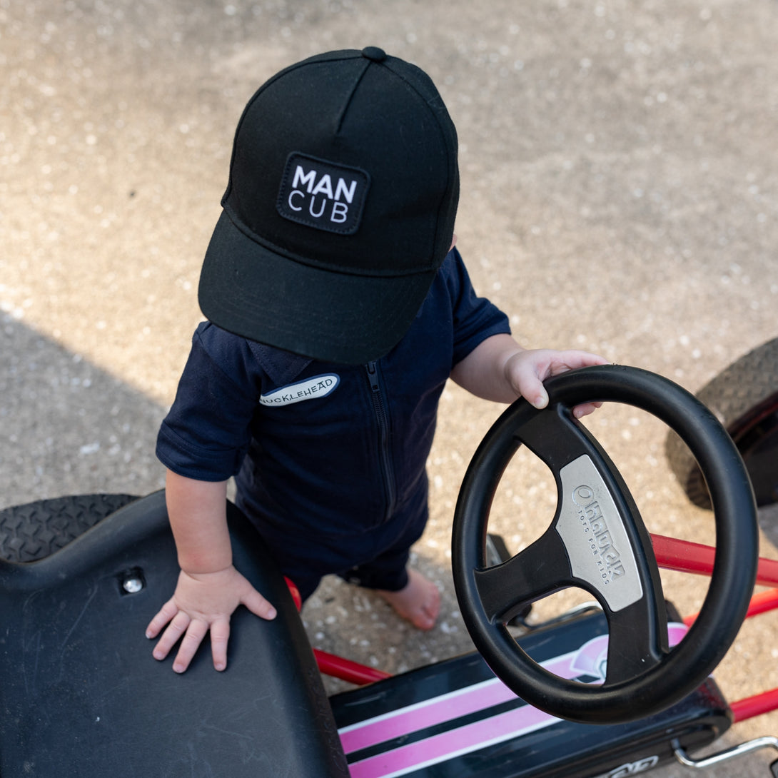 Image of Black Kids Trucker Hat with 'Man Cub' Patch: A cool and stylish accessory designed for kids. In classic black, it features an adorable 'Man Cub' patch on the front. Elevate your child's style with this fashionable hat, perfect for adding a playful touch to their outfits. Crafted with care, this black kids trucker hat with the 'Man Cub' patch is a must-have addition to their wardrobe, suitable for various occasions and everyday wear.