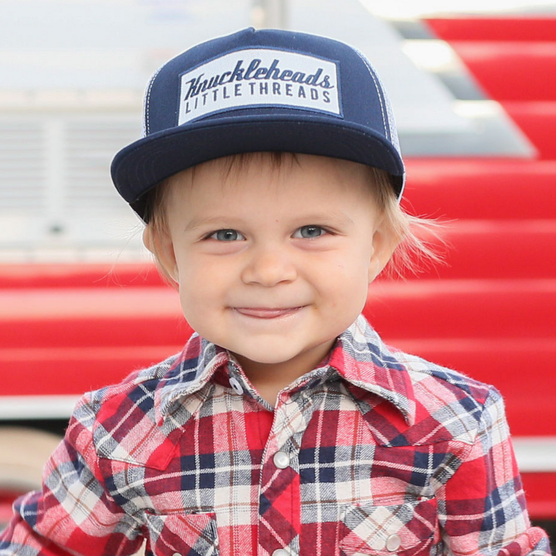Image of Navy Kids Trucker Hat with White Mesh and Rectangle Knuckleheads Patch: A stylish and versatile accessory designed for kids. In deep navy with crisp white mesh, it showcases a striking rectangle Knuckleheads patch on the front. Elevate your child's style with this fashionable hat, perfect for adding a touch of flair to their outfits while ensuring breathability.