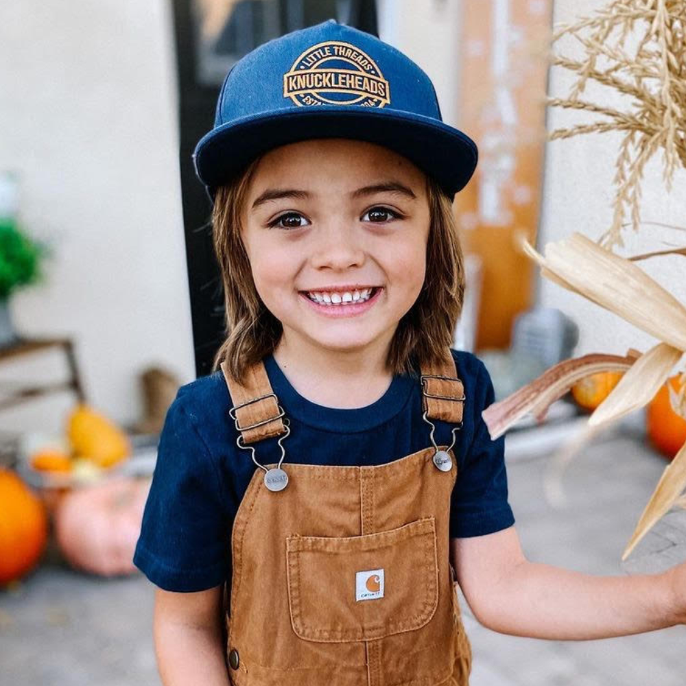 Image of Navy Kids Trucker Hat with Knuckleheads Patch: A versatile and stylish accessory designed for kids. In deep navy, it showcases a striking Knuckleheads patch on the front. Elevate your child's style with this fashionable hat, perfect for adding a touch of character to their outfits. Crafted with care, this navy kids trucker hat with the Knuckleheads patch is a must-have addition to their wardrobe, suitable for various occasions and everyday wear.