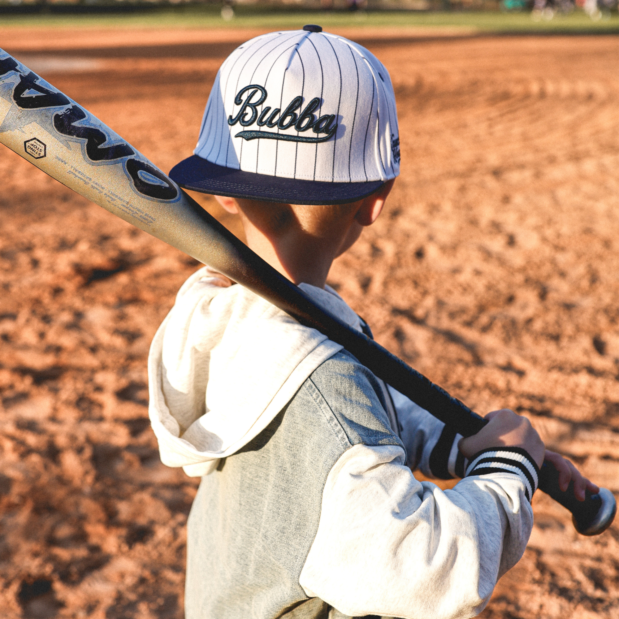 Lifestyle photo of toddler wearing Bubba embroidered snapback hat with navy pinstripes outdoors
