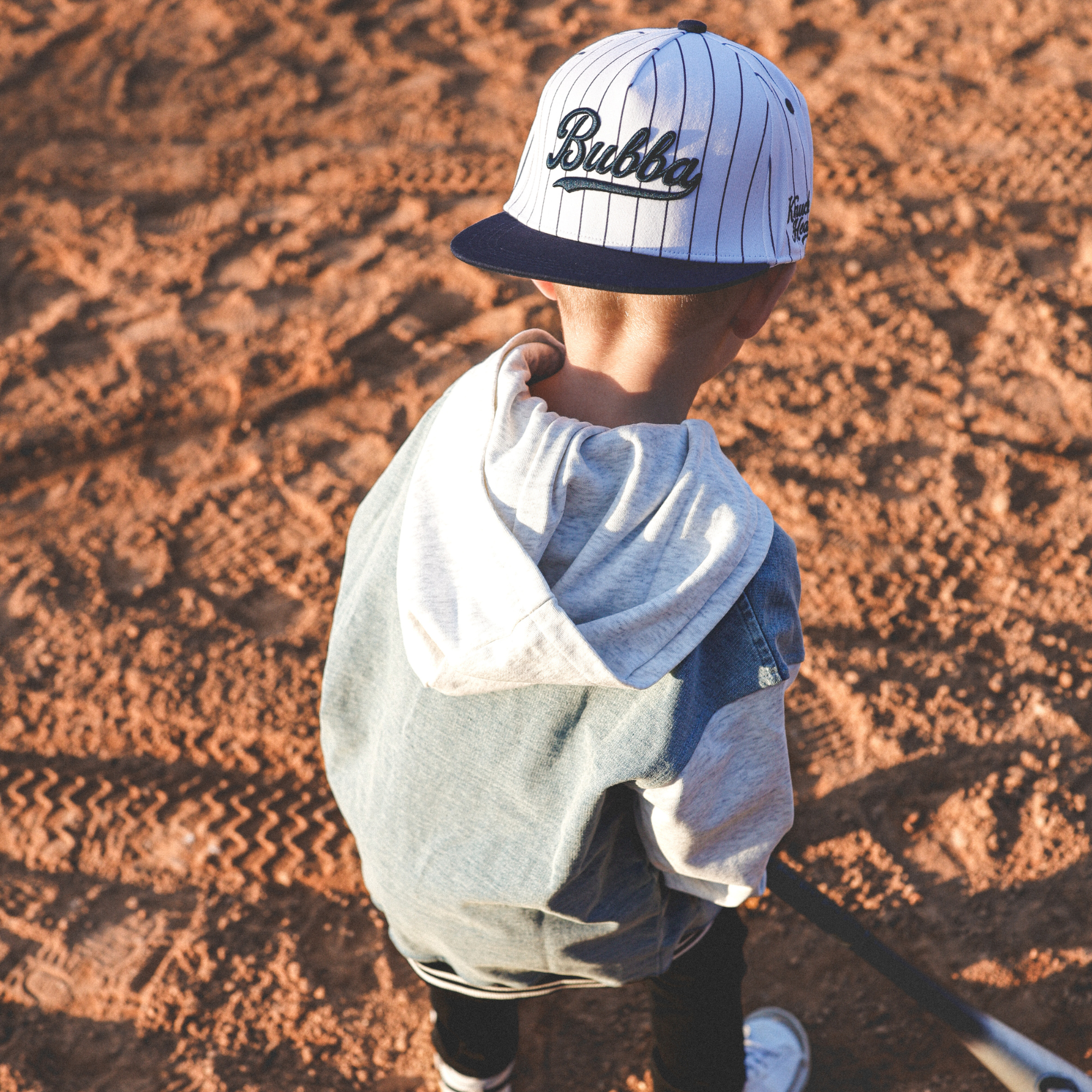 Lifestyle photo of toddler wearing Bubba embroidered snapback hat with navy pinstripes outdoors