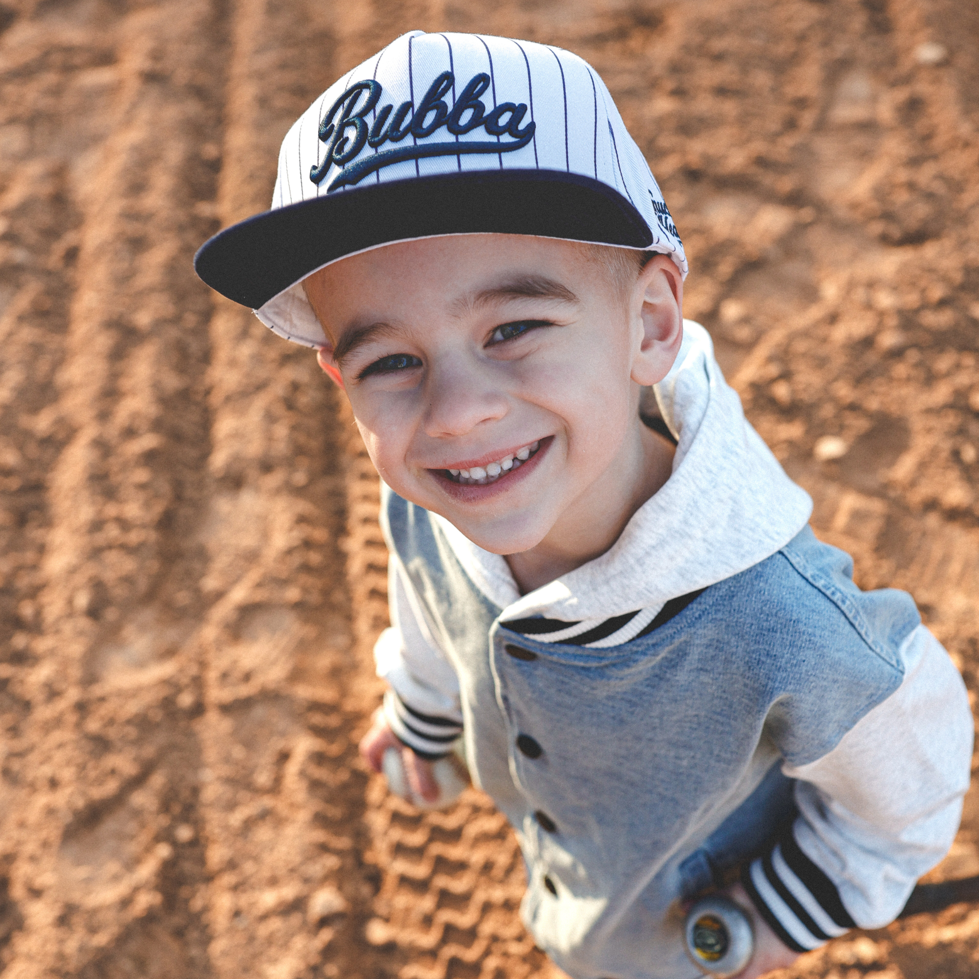 Lifestyle photo of toddler wearing Bubba embroidered snapback hat with navy pinstripes outdoors
