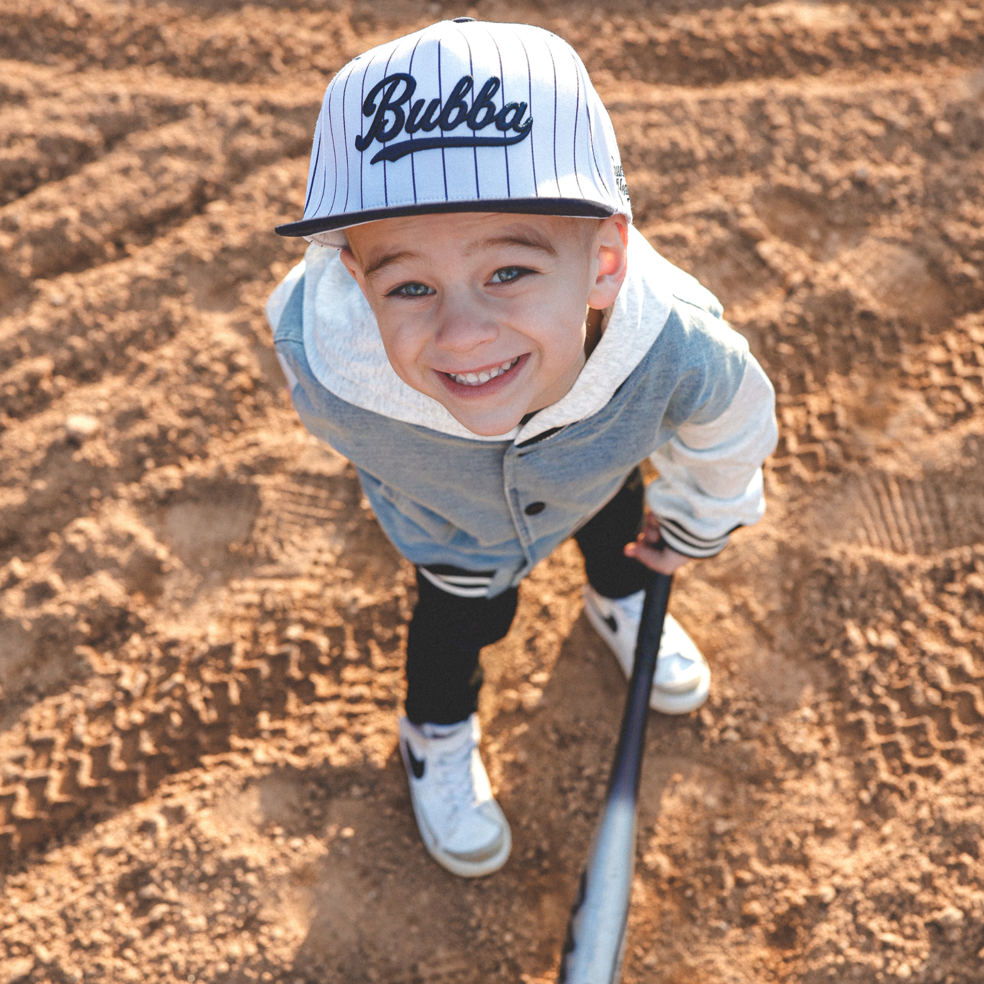 Lifestyle photo of toddler wearing Bubba embroidered snapback hat with navy pinstripes outdoors