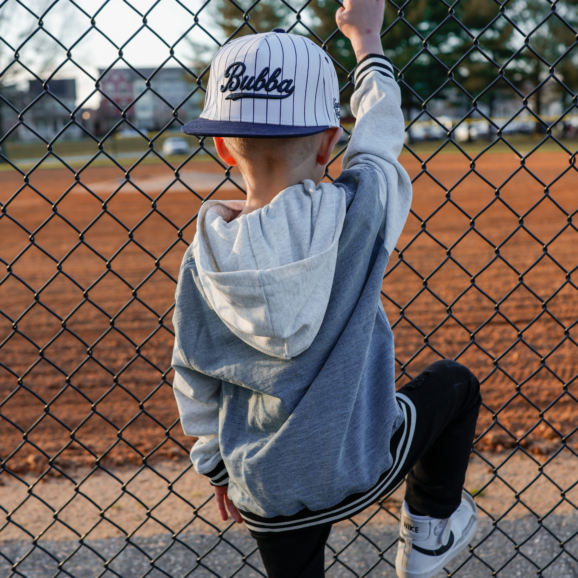 Lifestyle photo of toddler wearing Bubba embroidered snapback hat with navy pinstripes outdoors