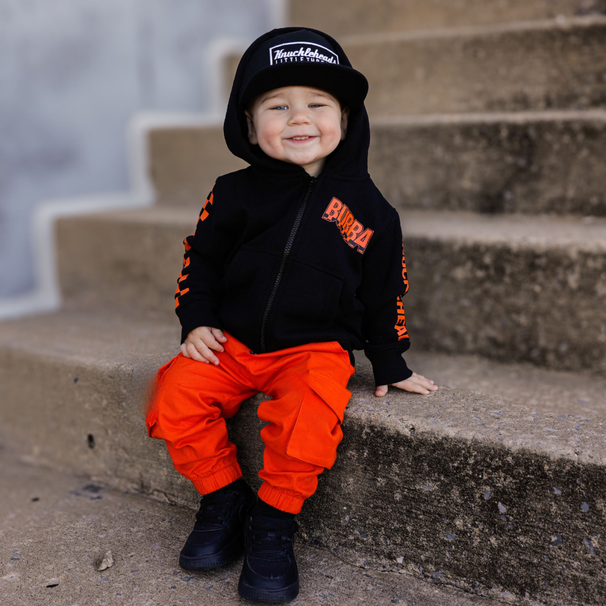 Knuckleheads Kids Bubba Zip Hoodie black graphic sweatshirt with orange logo and checker sleeves for toddlers and youth