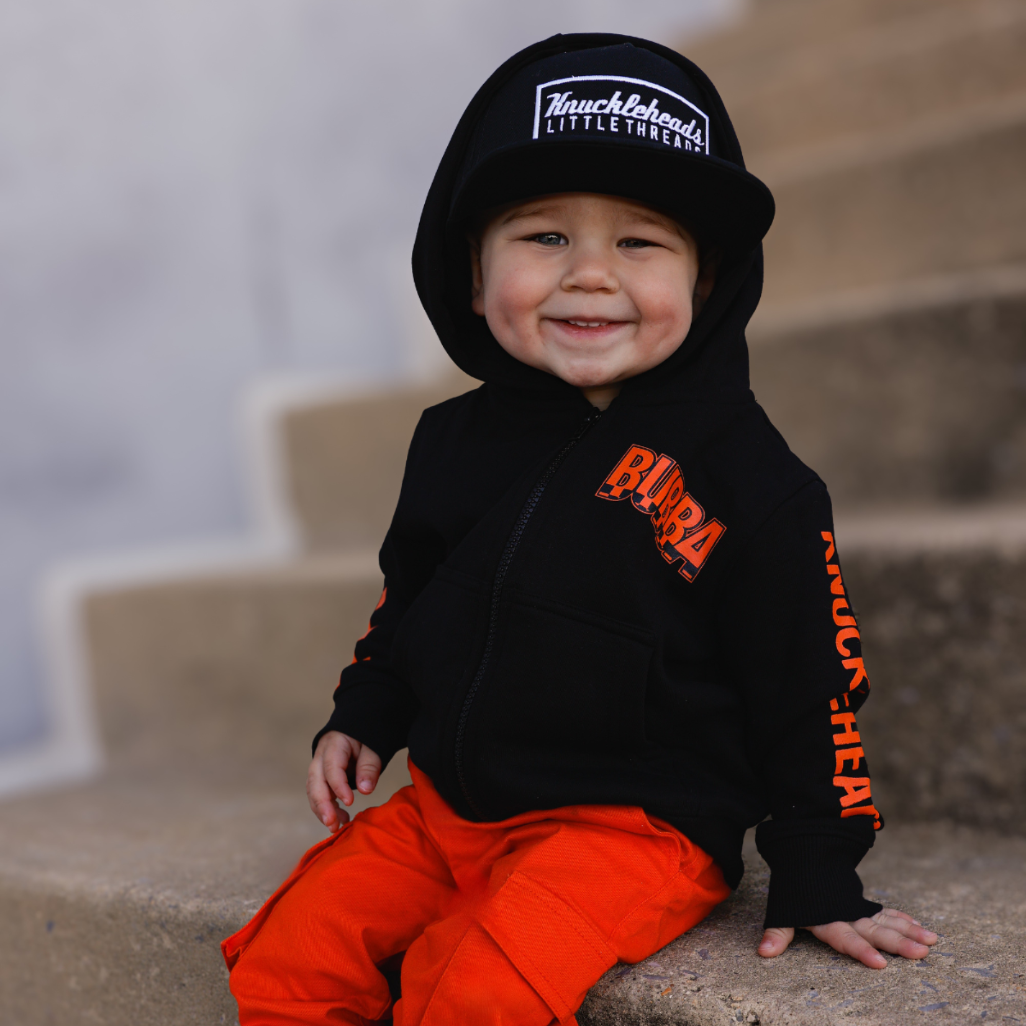 Knuckleheads Kids Bubba Zip Hoodie black graphic sweatshirt with orange logo and checker sleeves for toddlers and youth