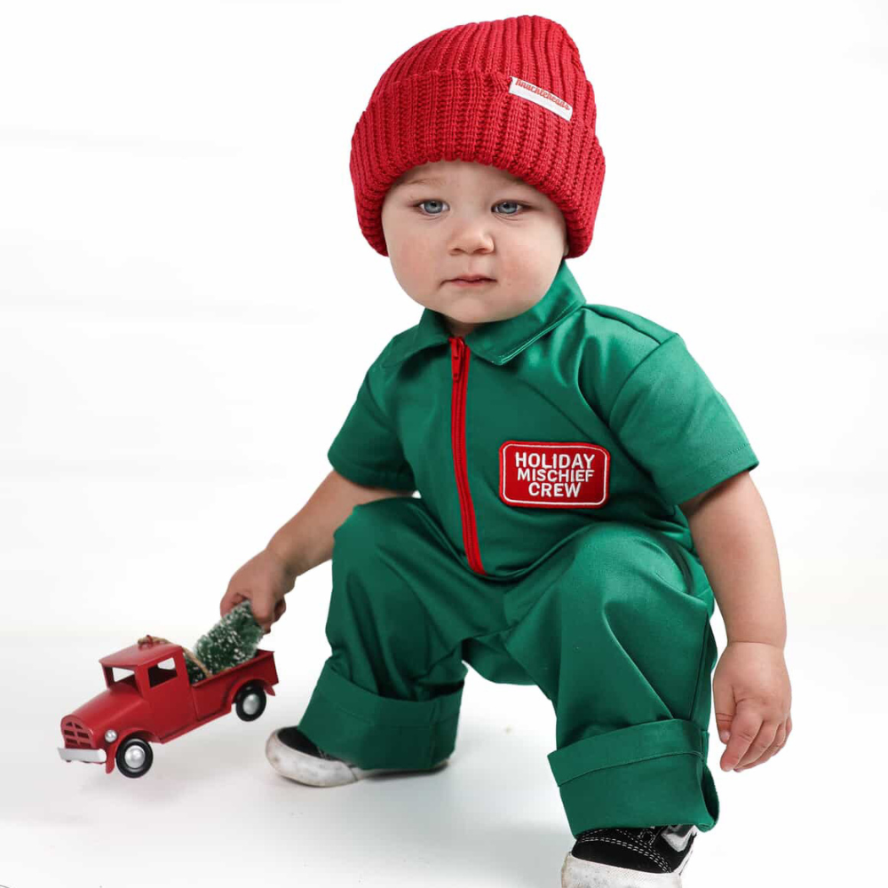 Holiday-themed toddler coverall in bright green with a red zipper and “Holiday Mischief Crew” patch, giving a playful mechanic look perfect for Christmas photos and adventures