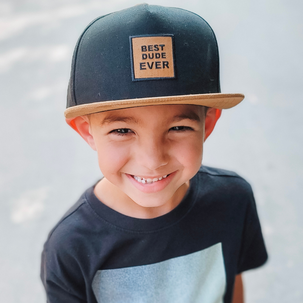 Image of Black with Brown Bill Kids Trucker Hat with 'Best Dude Ever' Patch: A trendy and stylish trucker hat designed for kids. The hat features a sleek black crown with a brown bill, adorned with a playful 'Best Dude Ever' patch on the front. Elevate your child's style with this fashionable and comfortable accessory, perfect for any outing or everyday wear. Crafted with care, this black trucker hat with brown bill and 'Best Dude Ever' patch is a must-have addition to their wardrobe.