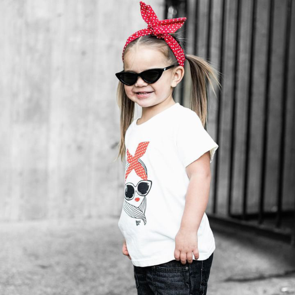 Image of Off-White Kids T-Shirt with Stylish Female Design: A fashionable and versatile addition to kids' wardrobes. This off-white-colored t-shirt features a captivating image of a stylish female adorned with red lipstick and sunglasses. Keep your child's style on point with this unique shirt, perfect for adding a touch of personality to their outfits. 