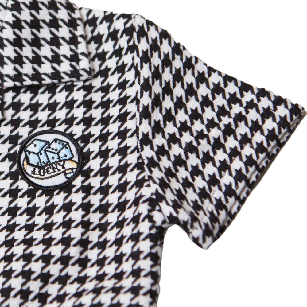 This image showcases delightful houndstooth kids' coveralls adorned with a charming Knuckleheads patch, adding a touch of whimsy to your child's wardrobe. These coveralls are not only fashionable but also comfortable, making them an ideal choice for your little one's everyday adventures.