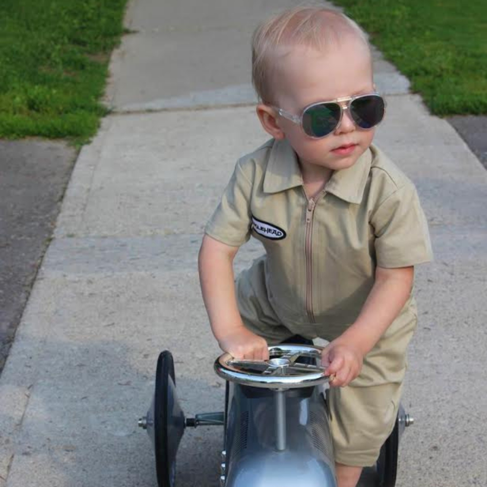This image showcases delightful khaki kids' coveralls adorned with a charming Knuckleheads patch, adding a touch of whimsy to your child's wardrobe. These coveralls are not only fashionable but also comfortable, making them an ideal choice for your little one's everyday adventures.
