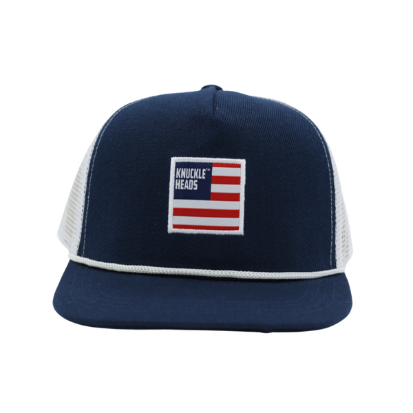 Image of Navy USA Kids Trucker Hat with Sun Mesh and Knuckleheads USA Flag Patch: A patriotic and practical trucker hat designed for kids. The hat comes in classic navy blue, featuring a sun mesh to keep them cool and comfortable. On the front, a striking USA flag patch by Knuckleheads proudly showcases their American spirit. Perfect accessory to elevate your child's style while providing sun protection during outdoor adventures.