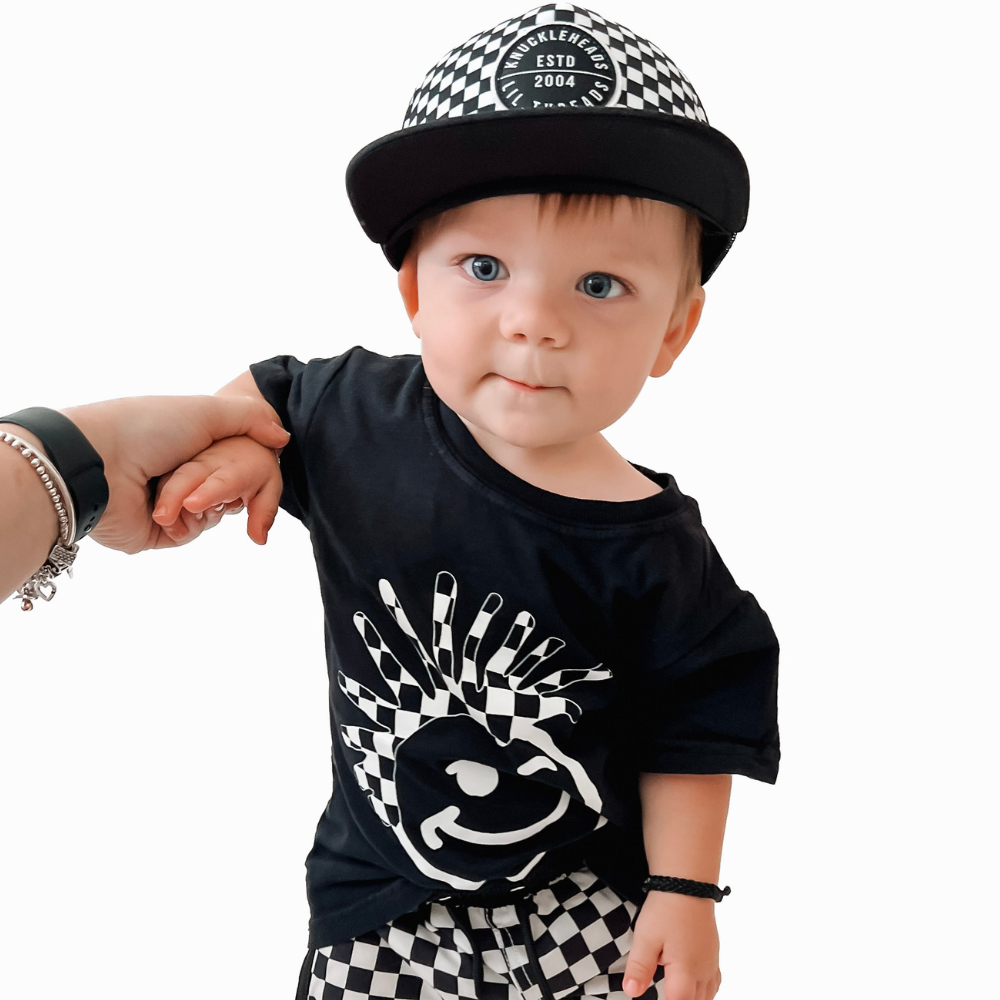 Image of Black Kids T-Shirt with Checkered Knuckleheads Logo: A cool and trendy wardrobe addition for kids. In classic black, it boasts a stylish checkered Knuckleheads logo on the front. Elevate your child's style with this fashionable t-shirt, perfect for adding a touch of edgy flair to their outfits. Crafted with care, this black kids t-shirt with the checkered Knuckleheads logo is a must-have piece, suitable for various occasions and everyday wear.