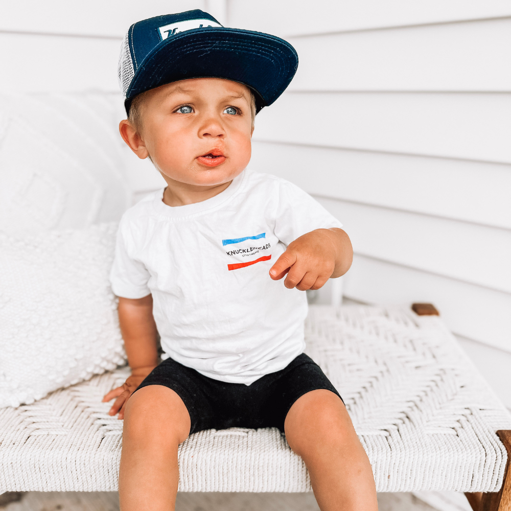 Image of Navy Kids Trucker Hat with White Mesh and Rectangle Knuckleheads Patch: A stylish and versatile accessory designed for kids. In deep navy with crisp white mesh, it showcases a striking rectangle Knuckleheads patch on the front. Elevate your child's style with this fashionable hat, perfect for adding a touch of flair to their outfits while ensuring breathability.