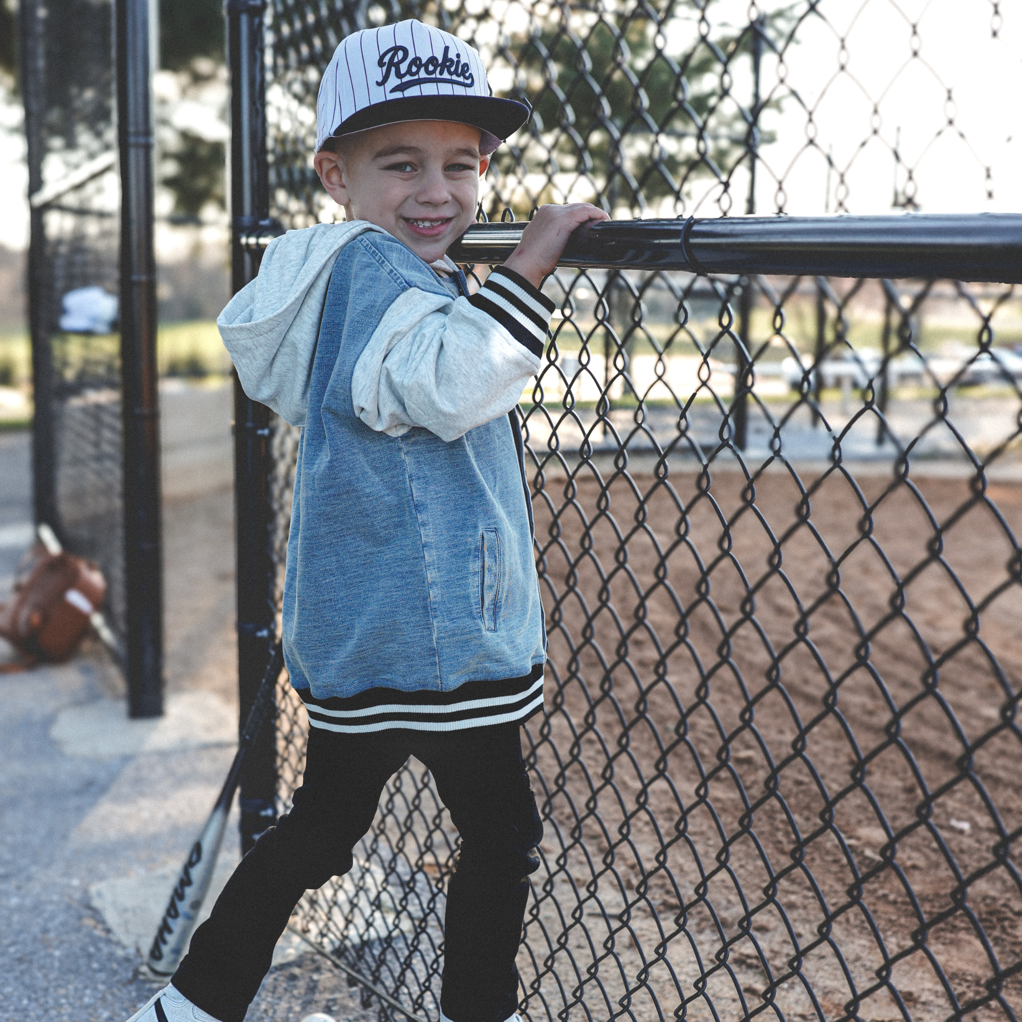 Lifestyle photo of toddler wearing Rookie snapback hat with navy pinstripes at baseball field