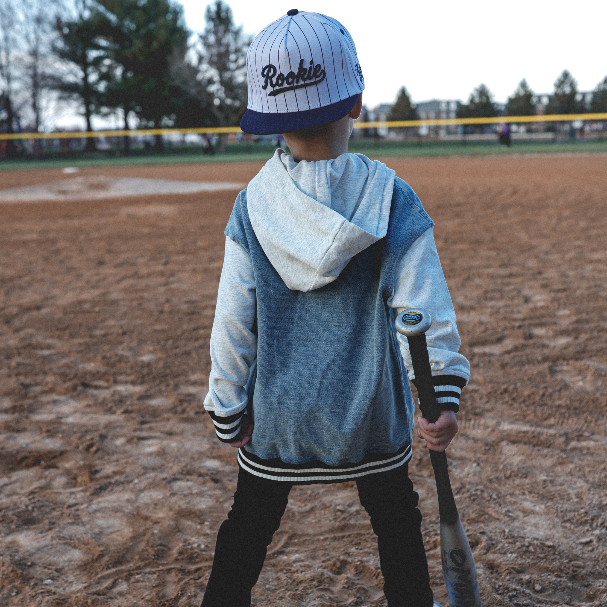 Lifestyle photo of toddler wearing Rookie snapback hat with navy pinstripes at baseball field