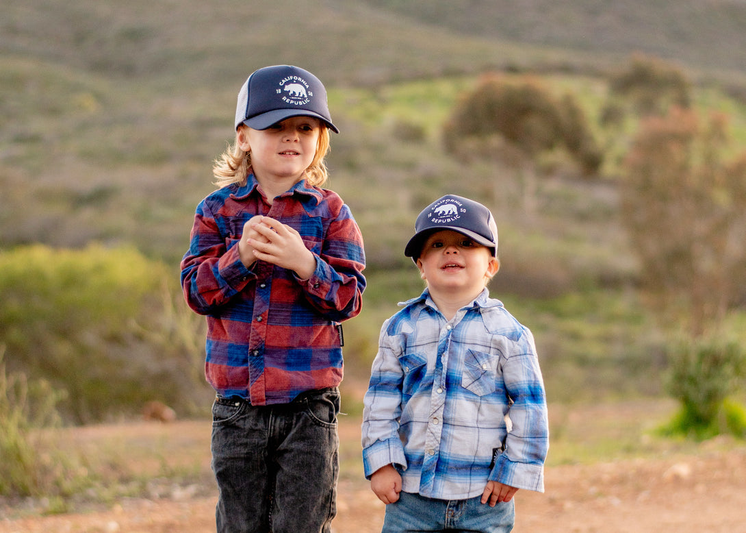 Image of Navy Kids Trucker Hat with California Republic Patch: A timeless and stylish accessory designed for kids. In classic navy, it features a captivating California Republic patch on the front. Elevate your child's style with this fashionable hat, perfect for showing their affection for the Golden State.