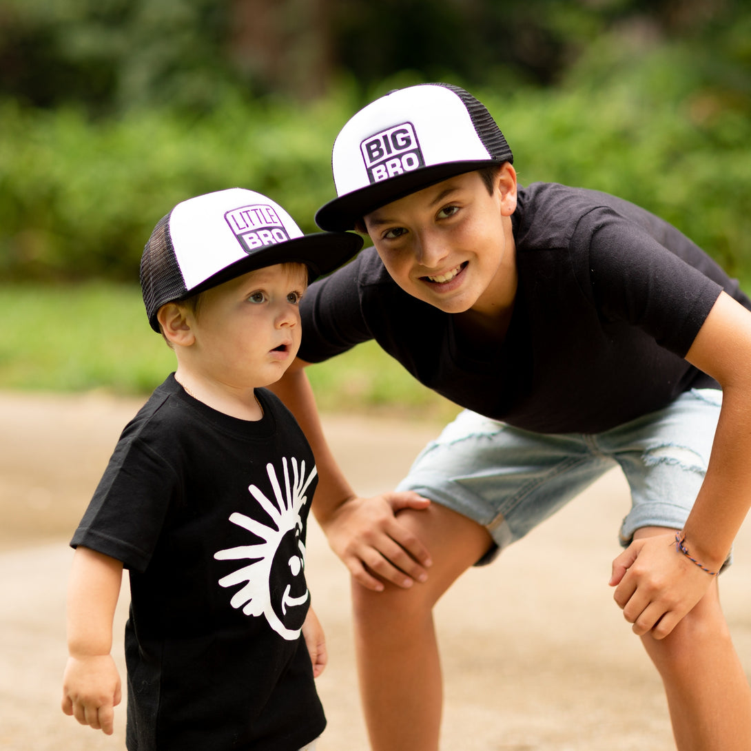 Image of Black and White Kids Trucker Hat with Sun Mesh and 'Big Bro' Patch: A stylish and comfortable trucker hat designed for kids. The hat features a classic black and white color scheme with sun mesh for breathability, adorned with a heartwarming 'Big Bro' patch on the front. Elevate your child's style with this trendy and endearing accessory, perfect for any adventure or everyday wear. Crafted with care, this black and white trucker hat with sun mesh and 'Big Bro' patch.