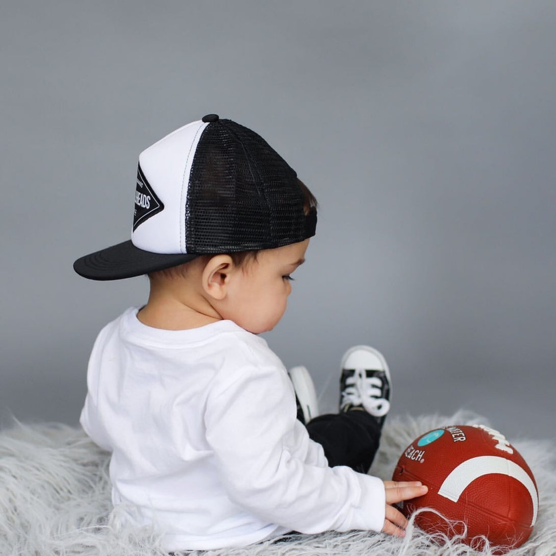 Introducing the 'Blake' Black and White Kids Trucker Hat with Knuckleheads Patch and Sun Mesh: A stylish and practical accessory designed for kids. The hat comes in sleek black, featuring a bold Knuckleheads patch on the front and sun mesh for breathability. Elevate your child's style with this fashionable and comfortable hat, perfect for any adventure or everyday wear. Crafted with care, the 'Blake' black trucker hat with Knuckleheads patch and sun mesh is a must-have addition to their wardrobe.
