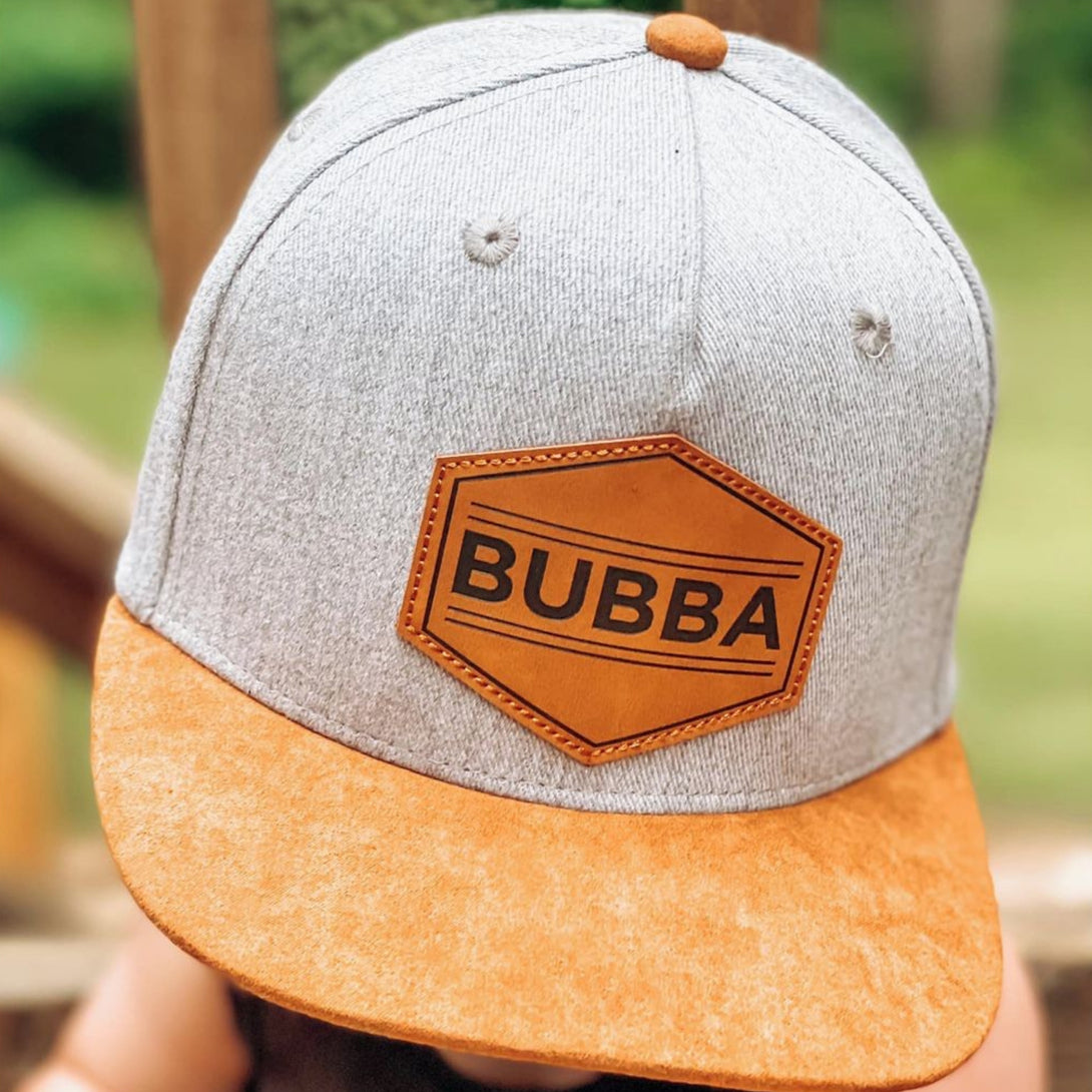Image of Grey-Brown Kids Trucker Hat with 'Bubba' Patch: A versatile and stylish accessory designed for kids. Combining elegant grey and warm brown tones, it features a playful 'Bubba' patch on the front. Elevate your child's style with this fashionable hat, perfect for adding a touch of contrast to their outfits. Crafted with care, this grey-brown kids trucker hat with the 'Bubba' patch is a must-have addition to their wardrobe, suitable for various occasions and everyday wear.