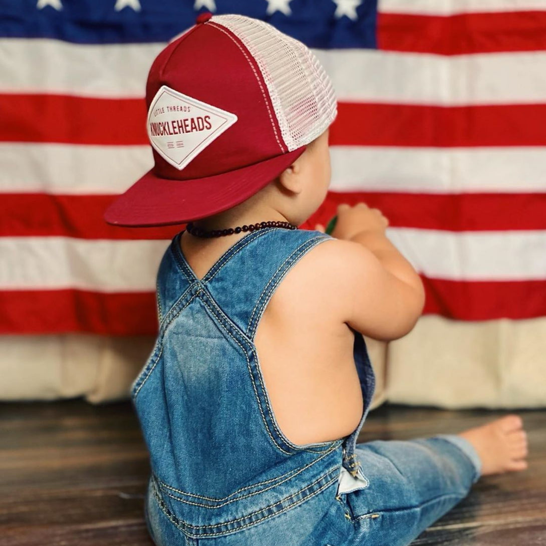 Image of Burgundy Kids Trucker Hat with Knuckleheads Patch: A sophisticated and stylish accessory designed for kids. In rich burgundy, it showcases a striking Knuckleheads patch on the front. Elevate your child's style with this fashionable hat, perfect for adding a touch of elegance to their outfits. Crafted with care, this burgundy kids trucker hat with the Knuckleheads patch is a must-have addition to their wardrobe, suitable for various occasions and everyday wear.
