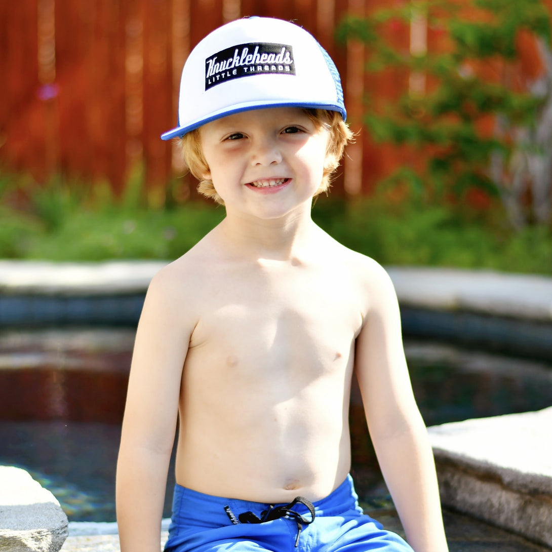 Image of Blue Kids Trucker Hat with White Mesh and Knuckleheads Patch: A trendy and practical accessory designed for kids. In a vibrant blue hue with crisp white mesh, it showcases a striking Knuckleheads patch on the front. Elevate your child's style with this fashionable hat, perfect for adding a pop of color to their outfits while ensuring breathability. 