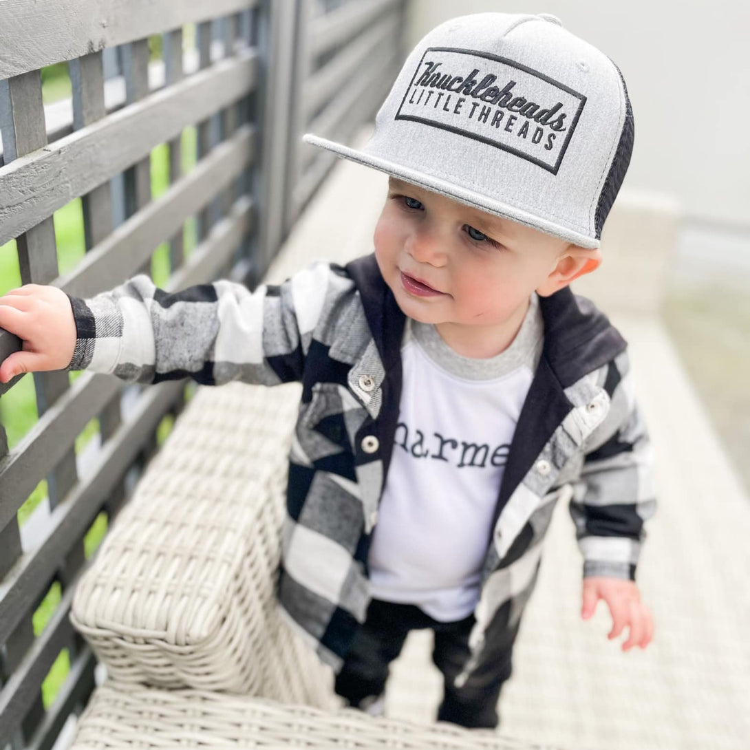 Image of Grey Kids Trucker Hat with Black Mesh and Knuckleheads Patch: A modern and stylish accessory designed for kids. In sleek grey with contrasting black mesh, it features a striking Knuckleheads patch on the front. Elevate your child's style with this fashionable hat, perfect for adding a touch of contrast to their outfits while ensuring breathability.