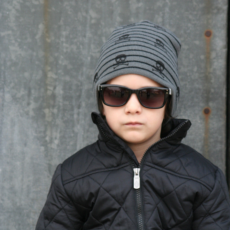 Image showcasing a grey beanie with skull motifs from Knuckleheads, designed for children. This unique beanie adds a touch of edginess with its skull pattern, while the Knuckleheads brand tag maintains its appeal for infants and toddlers. A distinctive choice within the collection of Infant hats, offering a blend of style and charm.