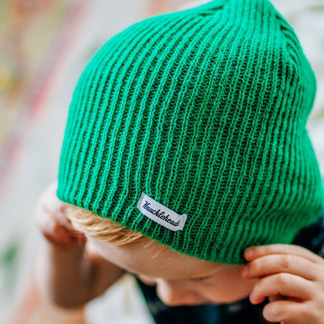 Image of a Knuckleheads Children's Green Beanie, highlighting its adaptable and cozy design made for infants and toddlers. Classic style adorned with the Knuckleheads brand tag. This Toddler beanie is part of a collection of charming Infant hats.