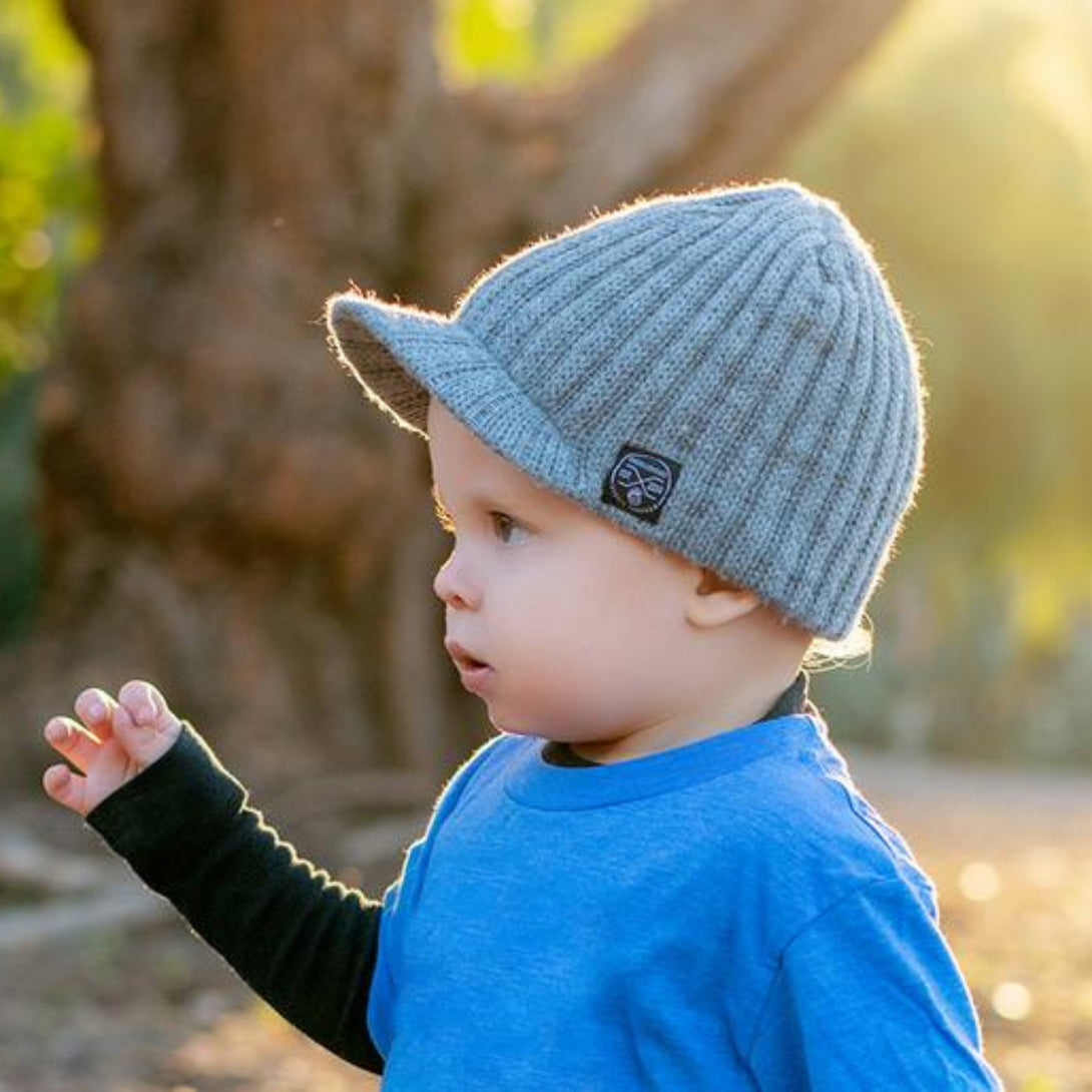 Image showcasing a grey beanie with a visor and Knuckleheads patch, designed for children. This versatile beanie combines style and functionality with its added visor and iconic Knuckleheads patch, making it an ideal choice for infants and toddlers. A standout piece in the collection of Infant hats, offering a perfect blend of practicality and charm.