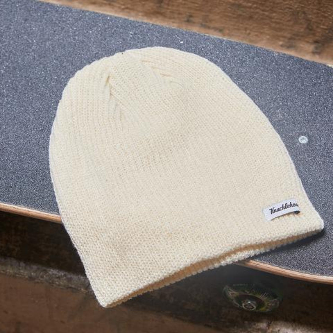 Image of a slouchy ivory beanie from Knuckleheads, designed for children. This versatile beanie offers a relaxed style with the Knuckleheads brand tag, suitable for infants and toddlers. A part of the charming collection of Infant hats for added appeal.