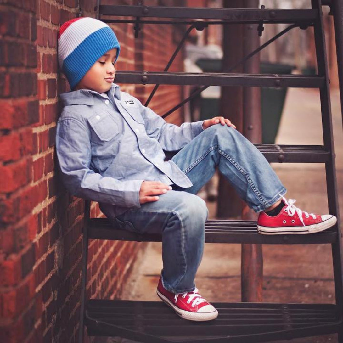 Image featuring a red, white, and blue striped beanie from Knuckleheads, tailored for children. This versatile beanie boasts a lively striped pattern, accompanied by the Knuckleheads brand tag, perfect for infants and toddlers. A spirited addition to the collection of Infant hats, enhancing its overall charm.