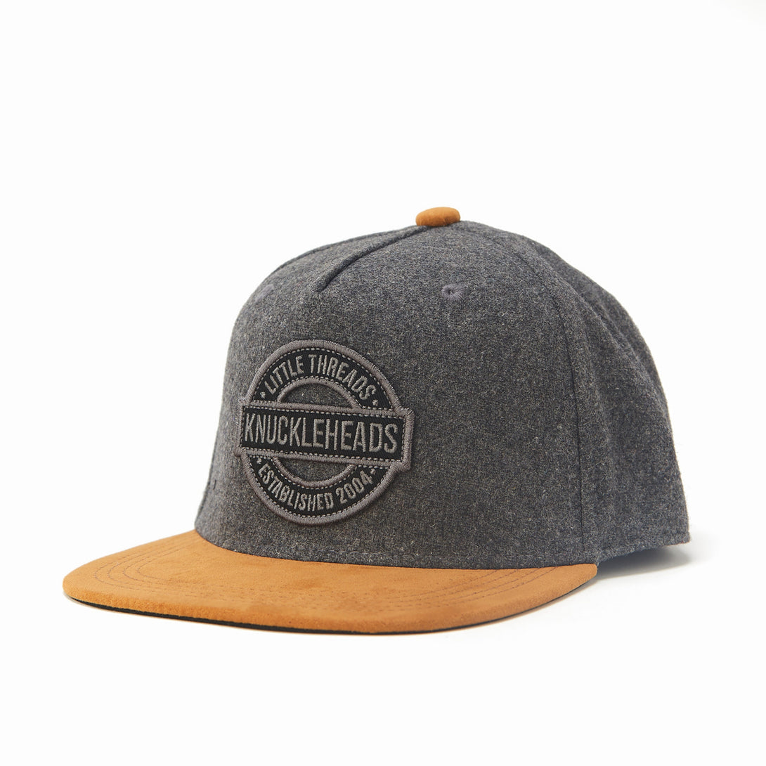 Image of Oat and Brown Kids Trucker Hat with Knuckleheads Patch: A rustic and stylish accessory designed for kids. In a charming oat and brown color combination, it showcases a striking Knuckleheads patch on the front. Elevate your child's style with this fashionable hat, perfect for adding a touch of natural flair to their outfits.