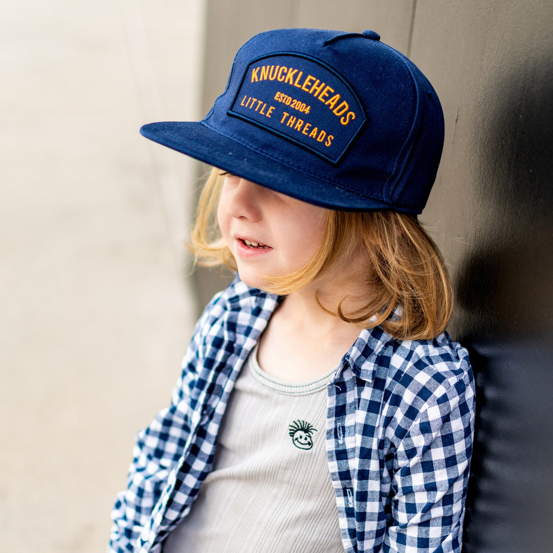 Image of Navy Kids Trucker Hat with Knuckleheads Patch: A stylish and versatile accessory designed for kids. In deep navy, it showcases a striking Knuckleheads patch on the front. Elevate your child's style with this fashionable hat, perfect for adding a touch of character to their outfits. Crafted with care, this navy kids trucker hat with the Knuckleheads patch is a must-have addition to their wardrobe, suitable for various occasions and everyday wear.