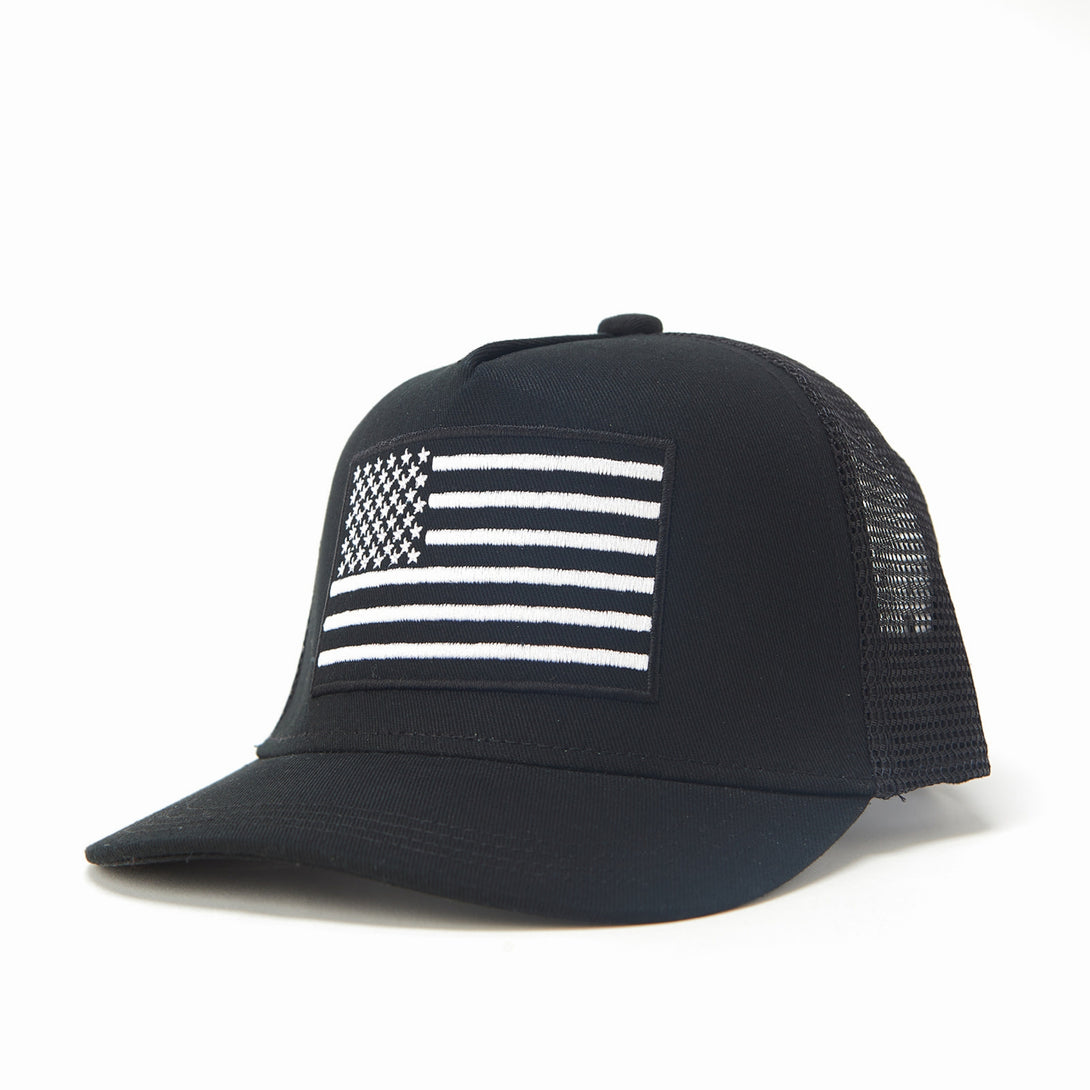 Image of Black Kids Trucker Hat with Black Mesh and USA Flag Patch: A patriotic and stylish accessory designed for kids. In classic black with sleek black mesh, it features a prominent USA flag patch on the front. Elevate your child's style with this fashionable hat, perfect for adding a touch of national pride to their outfits while ensuring breathability. 