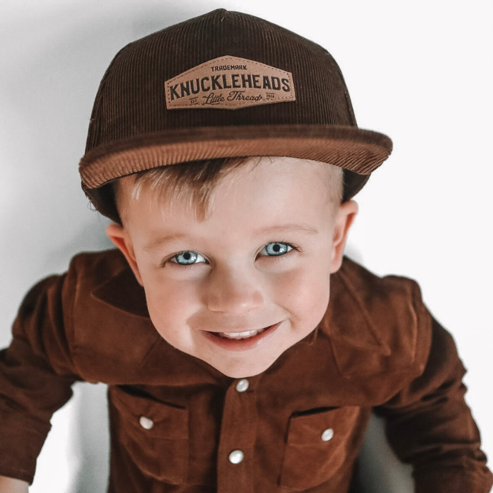 Introducing the 'Brayden' Brown Corduroy Kids Trucker Hat with Knuckleheads Patch: A trendy and stylish accessory tailored for kids. Crafted with a rich brown corduroy fabric, it showcases a cool Knuckleheads patch on the front. Elevate your child's style with this fashionable hat, perfect for adding texture to their outfits. Whether for outdoor escapades or everyday wear, the 'Brayden' brown corduroy trucker hat with Knuckleheads patch is a must-have addition to their wardrobe.